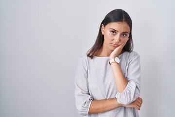 Young hispanic woman standing over white background thinking looking tired and bored with...