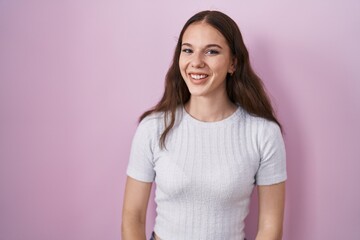 Fototapeta premium Young hispanic girl standing over pink background winking looking at the camera with sexy expression, cheerful and happy face.