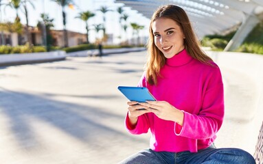 Young woman using touchpad sitting on bench at park