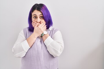 Plus size woman wit purple hair standing over white background shocked covering mouth with hands for mistake. secret concept.