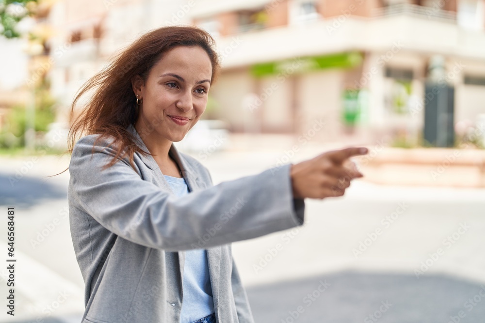 Poster Young woman executive pointing with finger at street