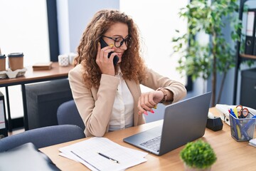 Young beautiful hispanic woman business worker talking on smartphone looking watch at office