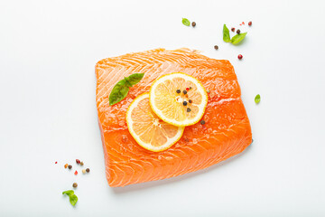 Fresh raw salmon marbled fillet isolated on white background with lemon, coarse salt, green herbs top view. Healthy nutrition and balanced diet.