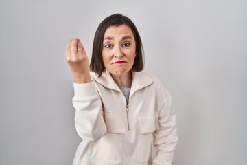Middle age hispanic woman standing over isolated background doing italian gesture with hand and fingers confident expression