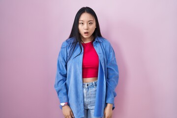 Young asian woman standing over pink background afraid and shocked with surprise and amazed expression, fear and excited face.