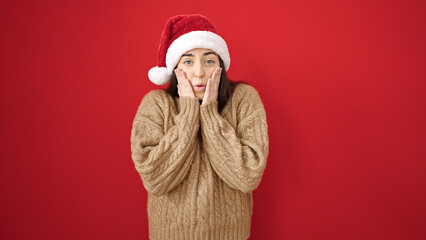 Young beautiful hispanic woman smiling confident wearing christmas hat over isolated red background