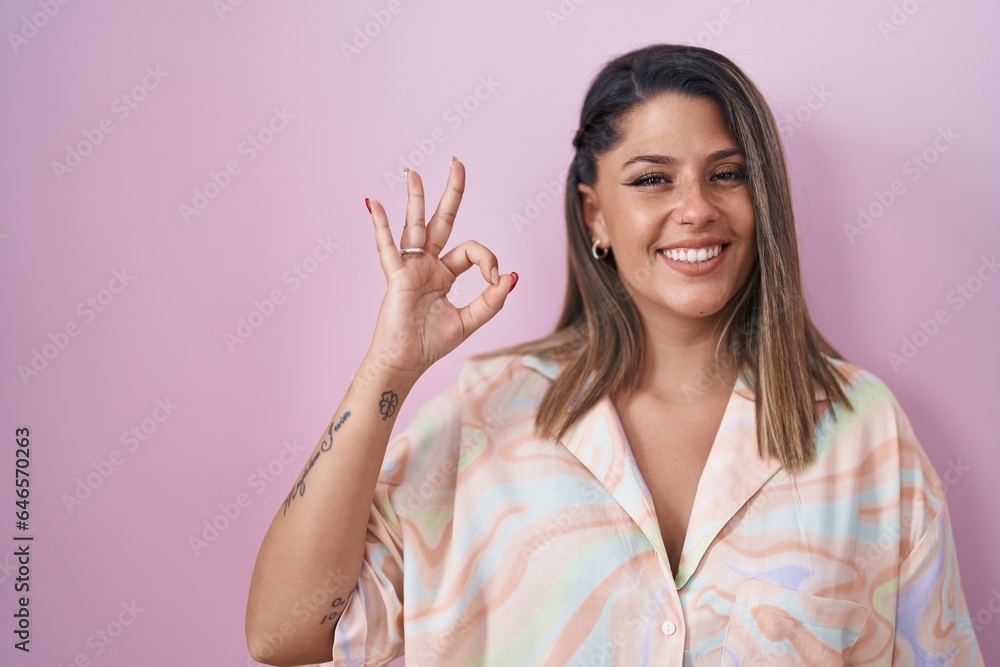 Sticker blonde woman standing over pink background smiling positive doing ok sign with hand and fingers. suc