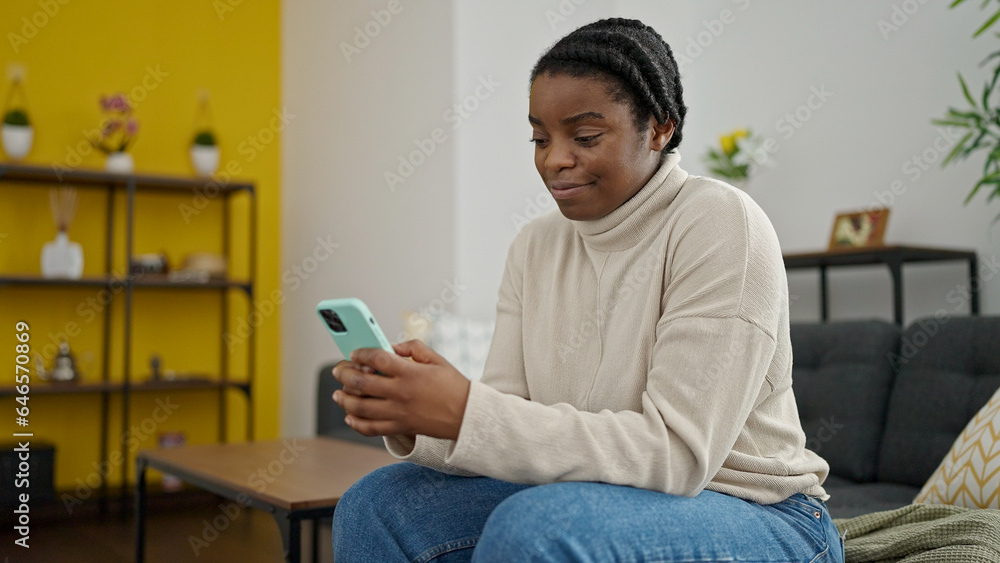 Canvas Prints African american woman using smartphone sitting on sofa at home