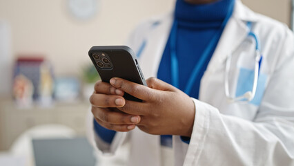 African american woman doctor using smartphone at clinic