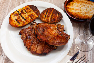 Roasted pork chop with vegetable garnish of grilled potatoes