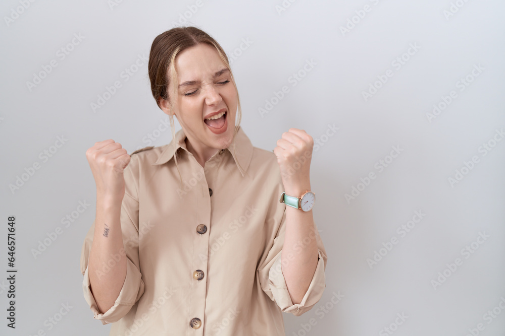 Poster young caucasian woman wearing casual shirt very happy and excited doing winner gesture with arms rai