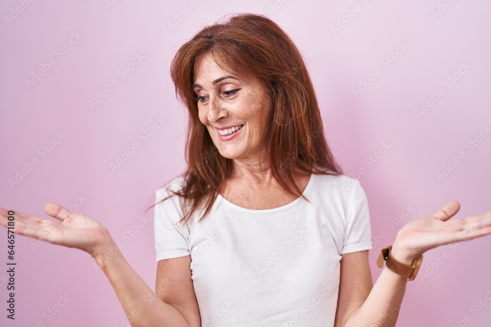 Canvas Prints Middle age woman standing over pink background smiling showing both hands open palms, presenting and advertising comparison and balance