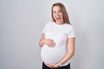 Young pregnant woman expecting a baby, touching pregnant belly celebrating crazy and amazed for...