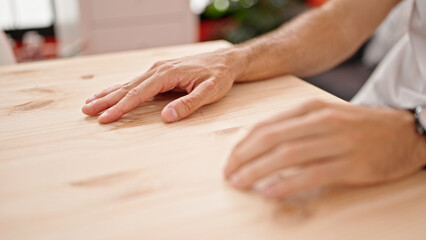 Young hispanic man touching table with fingers at dinning room