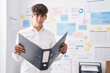 Young hispanic teenager business worker reading document at office