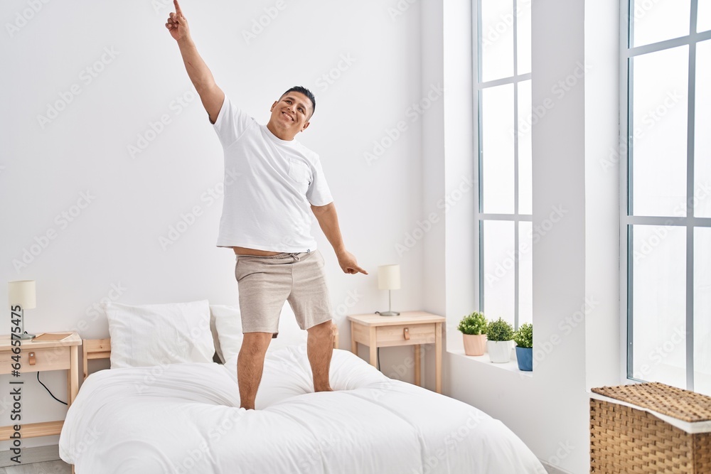 Poster Young latin man smiling confident dancing on bed at bedroom