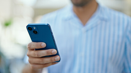 Young hispanic man using smartphone at street