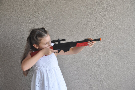 Menina brincando com arma de fogo de brinquedo, tiro ao alvo 
