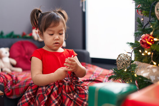Adorable chinese girl decorating christmas tree standing at home