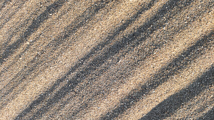 Sand surface with textured diagonal lines, close-up