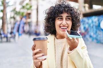 Young middle east woman excutive talking on the smartphone drinking coffee at street