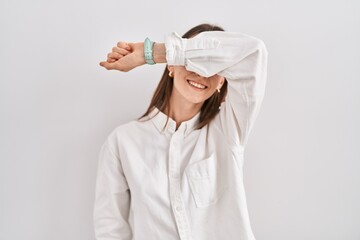 Young caucasian woman standing over isolated background covering eyes with arm smiling cheerful and...