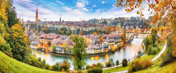 Fototapeta premium Amazing autumn view of Bern city on Aare river during evening with Pont de Nydegg bridge , cathedral of Bern and Nydeggkirche - Protestant church.
