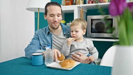 Father and son sitting on table having breakfast at dinning room