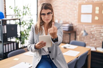 Young hispanic woman working at the office wearing glasses showing middle finger, impolite and rude...