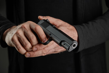 Male hand holding a gun on black background . A gun in a man's hand. defense or attack murderer or...