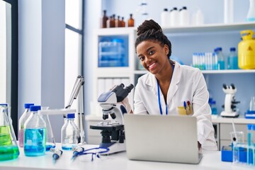 African american woman scientist using laptop working at laboratory