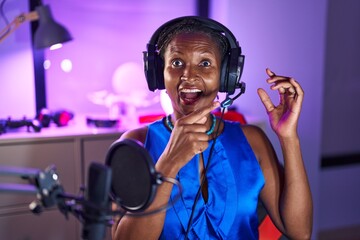 African woman with dreadlocks wearing headphones smiling happy pointing with hand and finger