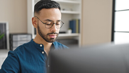 Fototapeta premium Young hispanic man business worker using computer with serious face at the office