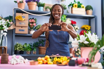 African american woman florist make photo by smartphone to bouquet of flowers and envelope letter at flower shop