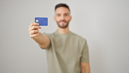 Young hispanic man smiling confident holding credit card over isolated white background