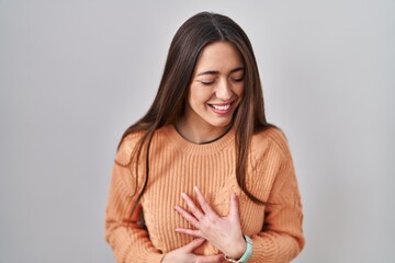 Obraz premium Young brunette woman standing over white background smiling and laughing hard out loud because funny crazy joke with hands on body.