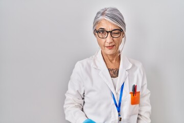 Middle age woman with grey hair wearing scientist robe winking looking at the camera with sexy...