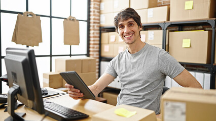 Young hispanic man ecommerce business worker using touchpad smiling at office