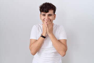 Fototapeta na wymiar Young non binary man wearing casual white t shirt laughing and embarrassed giggle covering mouth with hands, gossip and scandal concept