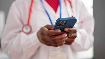African american woman doctor using smartphone at clinic