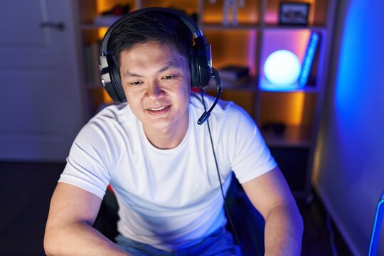 Young chinese man streamer playing video game using computer at gaming room