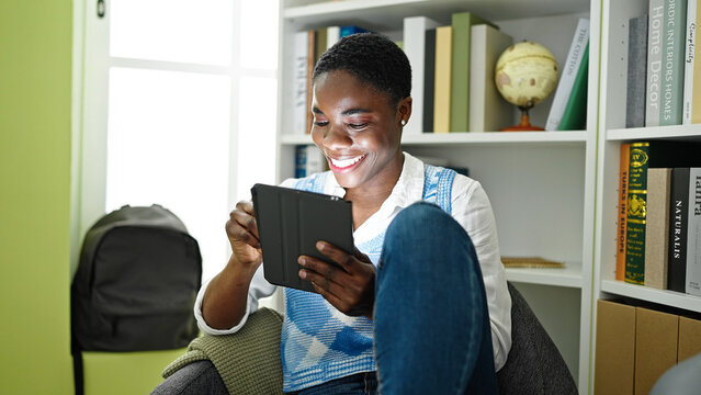 African american woman student using touchpad studying at library university
