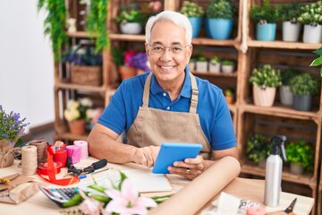 Middle age grey-haired man florist smiling confident using touchpad at florist