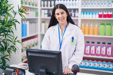 Young beautiful hispanic woman pharmacist smiling confident using computer at pharmacy