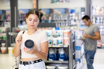 Fototapeta premium Female customer chooses can of paint in a hardware store
