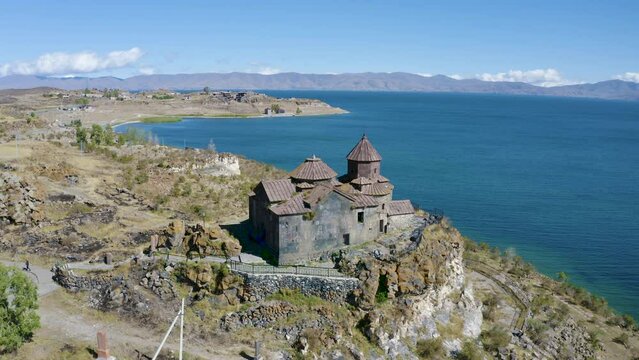 Forward reveal aerial shot of Hayravank Monastery and Sevan Lake on sunny summer day. Gegharkunik Province, Armenia.