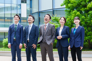 オフィスビルの前で笑うビジネスパーソン
