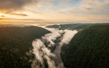Early morning sunrise view of the mist swirling over the Cheat river in the canyon seen from Coopers Rock State Park in West Virginia