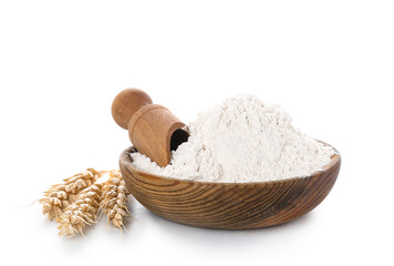 Wooden bowl with wheat flour, scoop and spikelets isolated on white background