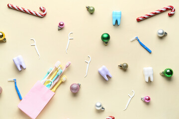 Bag with toothbrushes, dental floss and Christmas toys on beige background